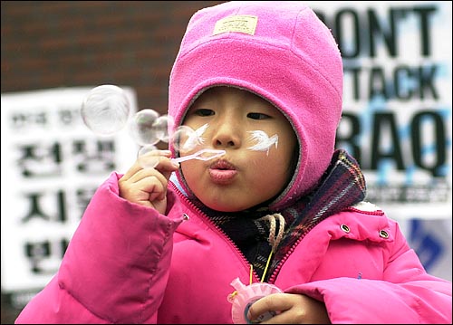 평화의 비둘기를 볼에 그려넣은 어린이가 비누방울을 날리고 있다. 